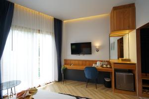 a room with a desk and a television and a table at Passion Resort Kiriwong in Khiriwong