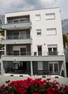 um edifício branco com cadeiras e flores em frente em Diamant Apartments em Baska Voda
