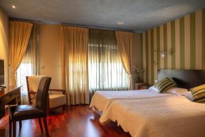 Habitación de hotel con cama, escritorio y ventana en Hostal Fuentefria, en Abejar