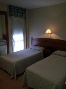 a hotel room with two beds and a window at Begoña Playa in Gijón