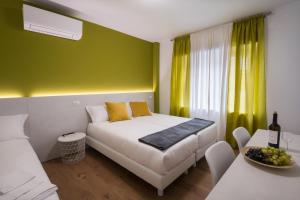 1 dormitorio con cama blanca y pared verde en ZONA 30 Bike Guesthouse, en Palmanova