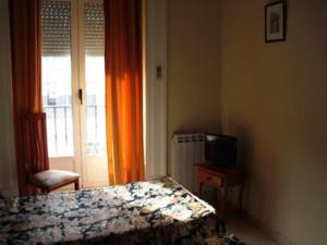 1 dormitorio con 1 cama, TV y ventana en Hostal del Mar, en Madrid