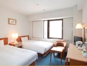 um quarto de hotel com duas camas e uma cadeira e uma janela em Smile Hotel Nihombashi Mitsukoshimae em Tóquio