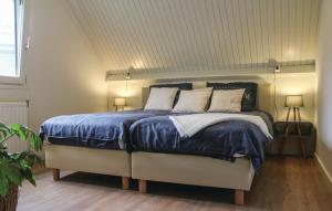 1 dormitorio con 1 cama con edredón azul y 2 lámparas en Vakantiewoning aan het Veerse meer, en Wolphaartsdijk