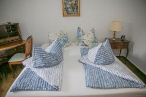 Una cama con cuatro almohadas azules y blancas. en Ferienwohnungen Schnabel im Herzen von Rottach-Egern, en Rottach-Egern