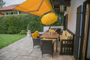 een houten tafel en stoelen met een gele paraplu bij Ferienwohnungen Schnabel im Herzen von Rottach-Egern in Rottach-Egern