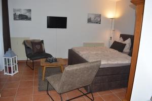 een slaapkamer met een bed, een stoel en een tv bij Hoffmann's Apartment in der Residenz Bocksbergblick in Hahnenklee-Bockswiese