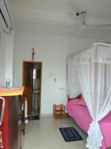 een slaapkamer met een roze bed met een baldakijn bij Sun Ocean Inn Mirissa in Mirissa