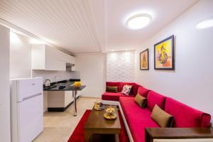 een woonkamer met een rode bank en een keuken bij Appart-hotel Marrakech Inn in Marrakesh