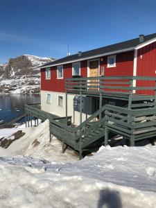 a red building with a deck in the snow at isi4u hostel, dogsled, snowmobiling in Sisimiut