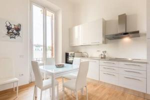 - une cuisine avec des placards blancs, une table et des chaises dans l'établissement Flawless Duomo Apartment, à Florence