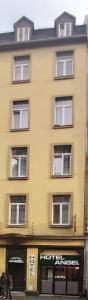 un grand bâtiment jaune avec des fenêtres donnant sur une rue dans l'établissement Angel Hotel, à Francfort-sur-le-Main