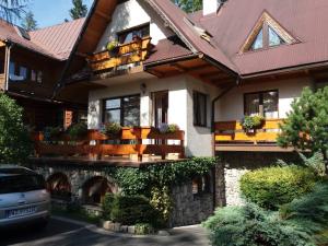 a house with a red roof and a car parked in front at Pokoje Gościnne U Wandy in Zakopane