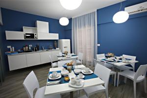 a dining room with blue walls and white tables and chairs at B&B High Definition in Pellaro