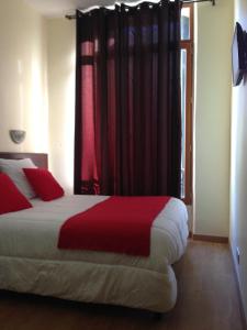 a bedroom with a bed with red sheets and a window at Hotel Victory in Marseille