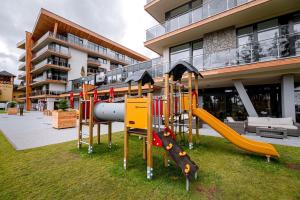 a playground in front of a building with slides at Apartmán LIANA Hrebienok C206 in Smokovce