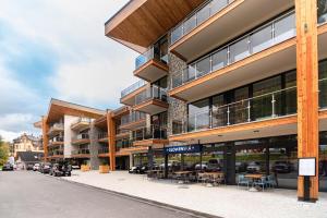 a large building with tables and chairs on a street at Apartmán LIANA Hrebienok C206 in Smokovce