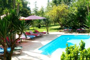 uma piscina num quintal com cadeiras e um guarda-sol em Can Portell by 123ole, B&B - Casa Rural em Sant Andreu del Terri