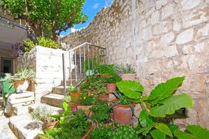 un jardín con macetas y una pared de piedra. en Villa Igrane en Igrane