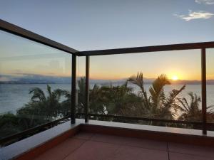 uma vista para o oceano a partir de uma varanda ao pôr-do-sol em Refúgio do Cacupé em Florianópolis