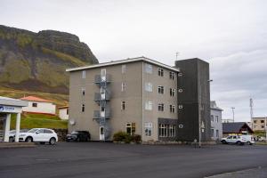 un grand bâtiment avec des voitures garées dans un parking dans l'établissement North Star Hotel Olafsvik, à Ólafsvík
