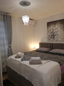 een slaapkamer met een groot bed en een kroonluchter bij Apartman ARINA in Zagreb