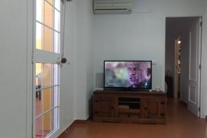 un téléviseur à écran plat posé sur un centre de divertissement en bois dans l'établissement APARTAMENTO VISTA MAR LA TORTUGA, à Tarifa