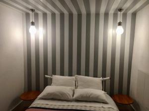 ギマランイスにあるCasinha Históricaのベッドルーム1室(ストライプの壁と2つの照明が備わるベッド1台付)