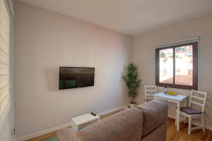 sala de estar con sofá y TV en la pared en Sonia´s City View en Santa Cruz de la Palma