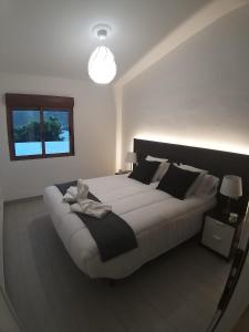 1 dormitorio con 1 cama blanca grande y espejo en CASA VISTAS TAMADABA en Agaete
