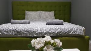 uma cama verde com duas almofadas e um vaso de flores em Villa Bratislava em Demir Kapija