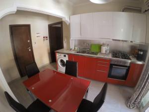 kuchnia z czerwonym stołem i kuchenką piekarnik w obiekcie Cozy and modern apartment w Korfu