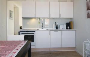 una cocina con armarios blancos y fregadero en Casa Blanca, en Gudhjem