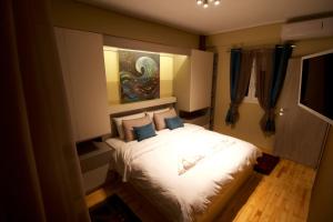 a bedroom with a bed with white sheets and blue pillows at Eros - Luxurious Apartment in Thessaloniki