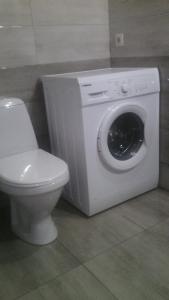 - un lave-linge blanc dans une salle de bains à côté des toilettes dans l'établissement Двухкомнатная квартира Лофт в Центре Одессы Новострой рядом с Вокзалом 5 минут до Дерибасовской и Аркадии, à Odessa