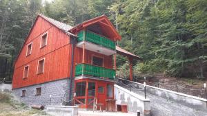 a red building with a green roof on a hill at Chata Colonada in Valča