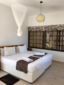 Un dormitorio con una gran cama blanca y una ventana en Villa Espanhola Bilene, en Vila Praia Do Bilene