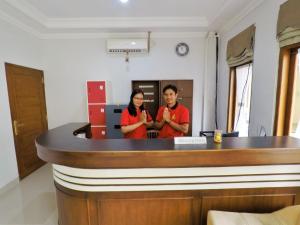 two people standing behind a bar in a room at Griya Alsis Residence in Yogyakarta