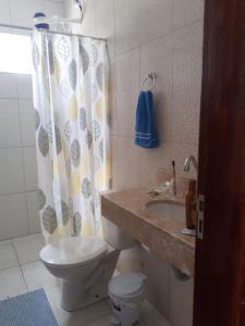 a bathroom with a toilet and a sink and a shower curtain at Casa Azul Gamboa do Morro in Gamboa +7 photos