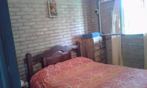 een bed in een kamer met een bakstenen muur bij Postal Serrana in Villa Parque Siquiman