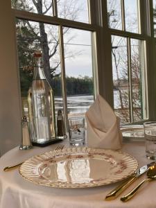 a table with a plate and a bottle and a window at Follansbee Inn in North Sutton