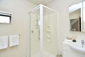 baño blanco con ducha y lavamanos en Hagley Apartment - Christchurch Holiday Homes en Christchurch