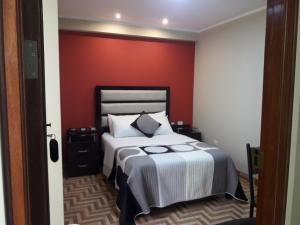 1 dormitorio con 1 cama con pared roja en Gavina Inn Hotel, en Tacna