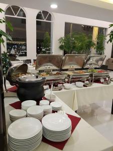 a buffet with white plates and a pot of food at Apple Hotel Three - near PNH airport in Phnom Penh