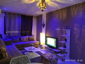 a living room with a couch and a tv at Opéra Appartement, Hivernage Marrakech. in Marrakesh