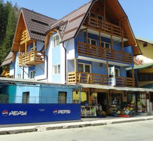 a large building with a store in front of it at Pensiunea Aurora -Hostel Voineasa in Voineasa