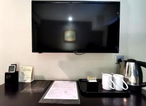 a desk with a television on a wall with a coffee pot at Kimberley Hotel Georgetown in George Town