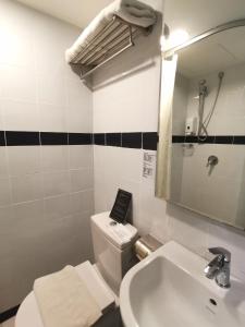 a bathroom with a sink and a toilet and a mirror at Kimberley Hotel Georgetown in George Town