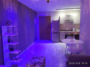 une cuisine avec éclairage violet, table et chaises dans l'établissement Opéra Appartement, Hivernage Marrakech., à Marrakech