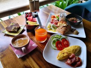 a wooden table with two plates of food and drinks at The Lazy Lodge in Ko Lanta